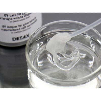 Earmold being dipped into Detax 04247 Luxaprint Flex Coat UV Lacquer